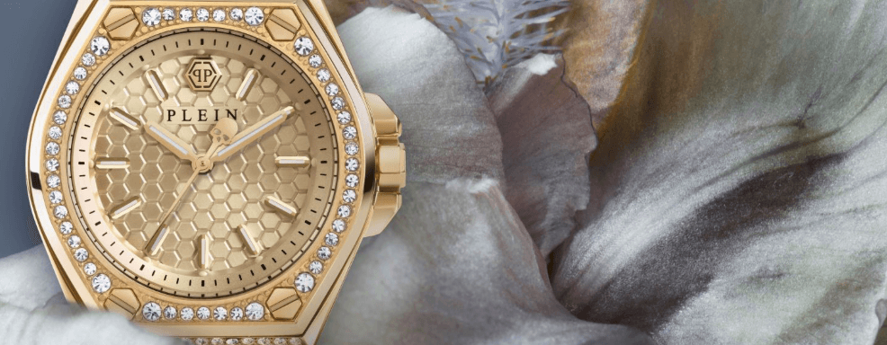 Goldfarbene Armbanduhr von Philipp Plein mit Kristallsteinen am Gehäuse, Wabenmuster im Zifferblatt, auf weißer Blütenblatt-Oberfläche