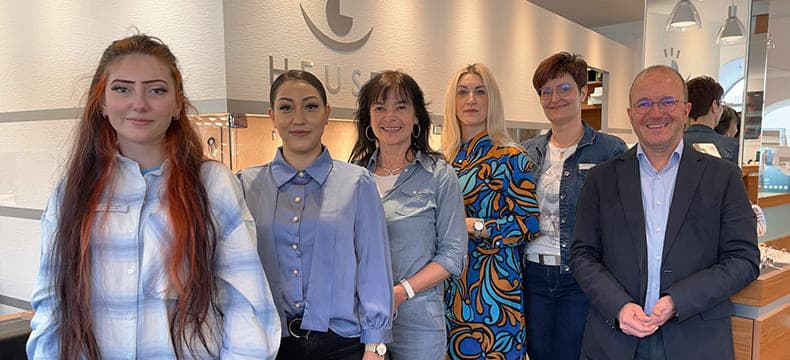 Freundliches Team von Juwelier Heuser im modernen Verkaufsraum vor Vitrinen mit Schmuck und Uhren.
